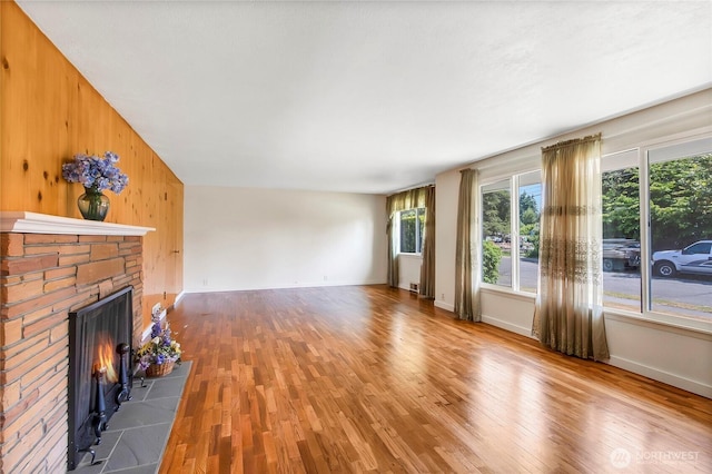 220 Alder Ave, Sumner, WA 98390 - unfurnished living room with wood finished floors, plenty of natural light, a fireplace, baseboards, and wood walls