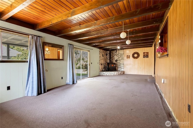 220 Alder Ave, Sumner, WA 98390 - carpeted empty room with a wood stove, plenty of natural light, wooden walls, and wooden ceiling with exposed beams