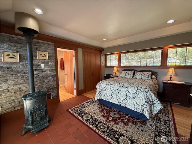 115 15th St SW, Long Beach, WA 98631 - tiled bedroom with a wood stove, multiple windows, recessed lighting, a tray ceiling, and ensuite bath