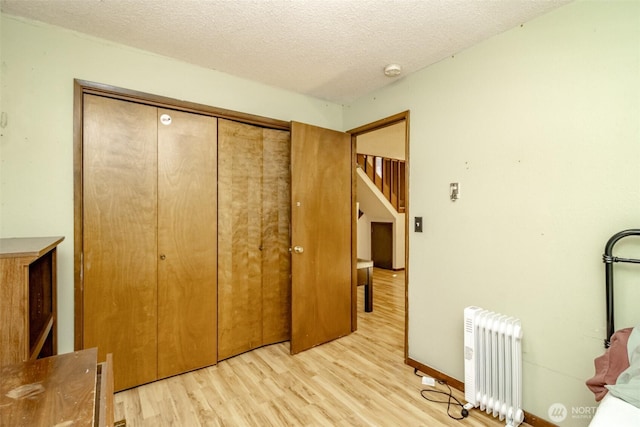 2111 SW Silvan View Ct SW, Olympia, WA 98512 - bedroom featuring radiator heating unit, light wood-style flooring, a closet, and a textured ceiling