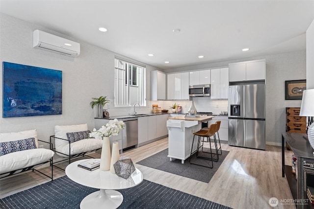 2527 29th Ave S Unit A, Seattle, WA 98144 - kitchen featuring appliances with stainless steel finishes, a wall mounted air conditioner, light wood-style flooring, a breakfast bar area, and recessed lighting