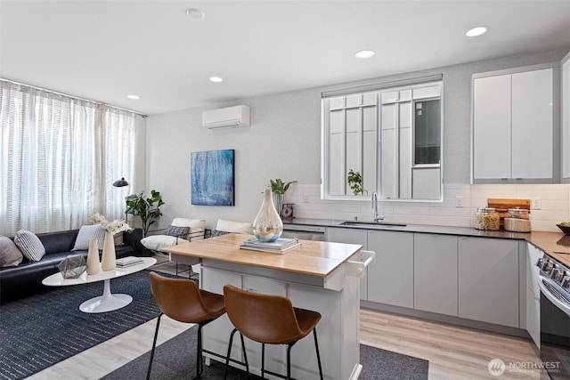 2527 29th Ave S Unit A, Seattle, WA 98144 - kitchen featuring a sink, a breakfast bar area, light wood-style flooring, a wall mounted AC, and backsplash