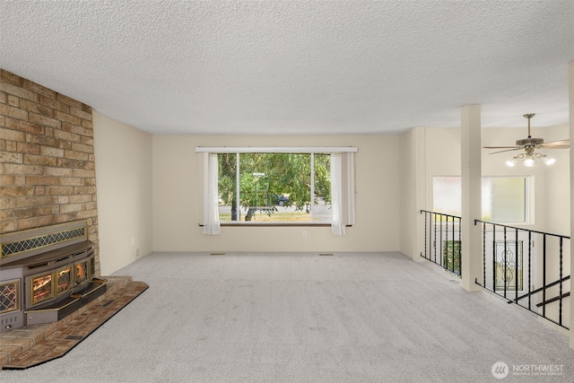 17122 40th Ave W, Lynnwood, WA 98037 - unfurnished living room with carpet flooring, a textured ceiling, ceiling fan, and a wood stove