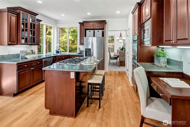 1122 140th Ave SE, Bellevue, WA 98005 - kitchen featuring light wood-style floors, stainless steel appliances, a kitchen bar, glass insert cabinets, and a center island