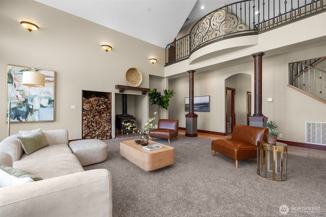 24022 SE 384th St, Enumclaw, WA 98022 - living room featuring a wood stove, high vaulted ceiling, arched walkways, decorative columns, and baseboards