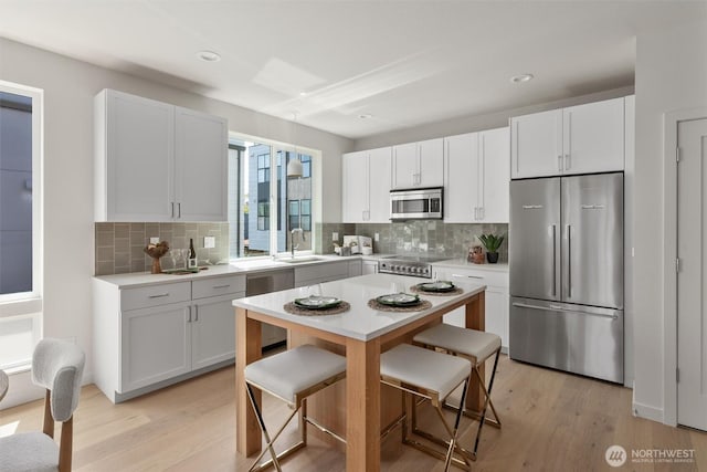 4521A Bagley Ave N, Seattle, WA 98103 - kitchen with appliances with stainless steel finishes, light countertops, a breakfast bar area, light wood-style flooring, and recessed lighting