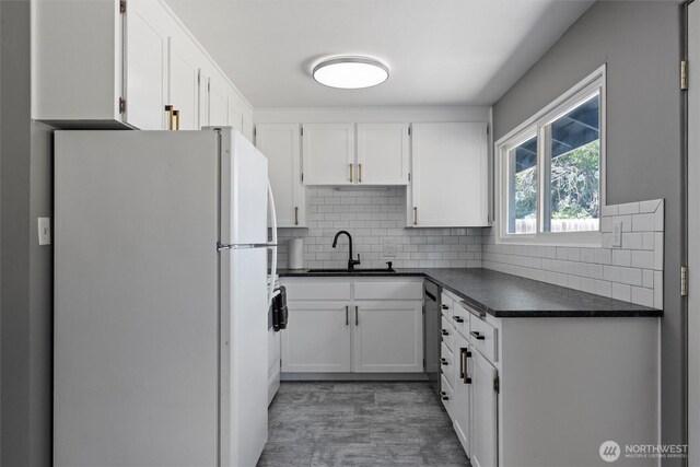 1115 S Evergreen Dr, Moses Lake, WA 98837 - kitchen with freestanding refrigerator, a sink, dark countertops, dishwasher, and white cabinetry