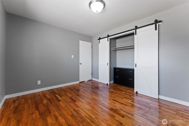 1115 S Evergreen Dr, Moses Lake, WA 98837 - unfurnished bedroom featuring a barn door, wood finished floors, baseboards, and a closet