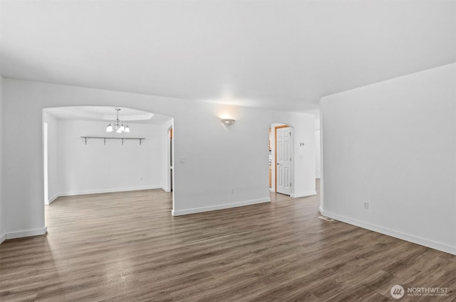 13924 Dogwood Ct, Sultan, WA 98294 - unfurnished living room featuring arched walkways, a chandelier, wood finished floors, and baseboards