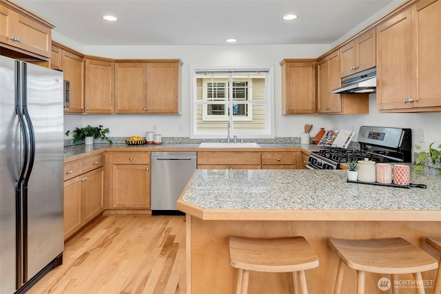 1824 23rd Ave Unit B, Seattle, WA 98122 - kitchen with stainless steel appliances, under cabinet range hood, a sink, light wood-style floors, and a peninsula
