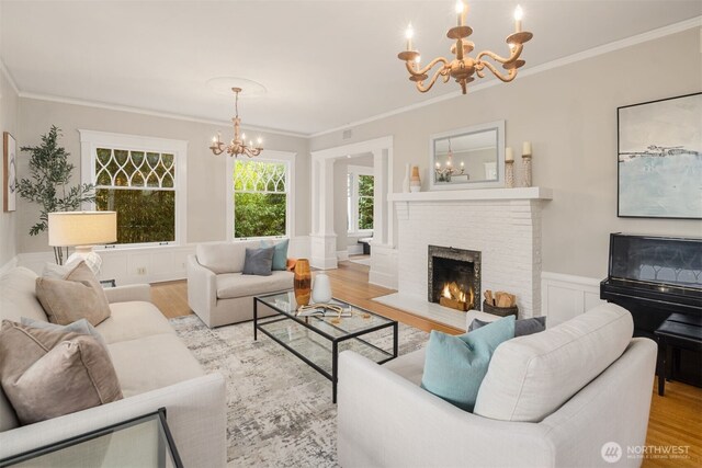 1611 Mcgilvra Blvd E, Seattle, WA 98112 - living room with a chandelier, wood finished floors, crown molding, a brick fireplace, and wainscoting