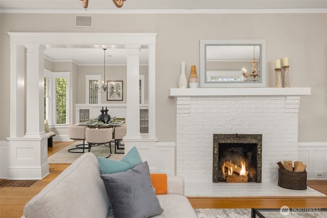1611 Mcgilvra Blvd E, Seattle, WA 98112 - living room with wood finished floors, a chandelier, crown molding, ornate columns, and a fireplace