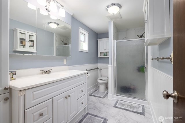 23696 Lake Dr, Mount Vernon, WA 98273 - bathroom featuring vanity, marble finish flooring, a wainscoted wall, a stall shower, and toilet