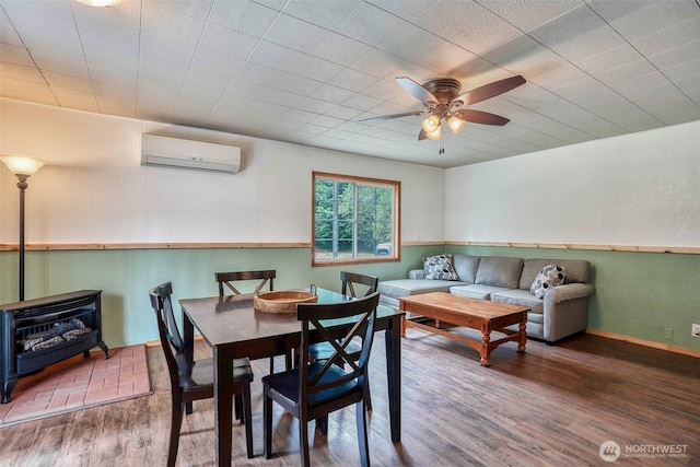 14938 Frenchie Ln SE, Yelm, WA 98597 - dining space featuring a wall mounted AC, wood finished floors, a ceiling fan, and a wood stove