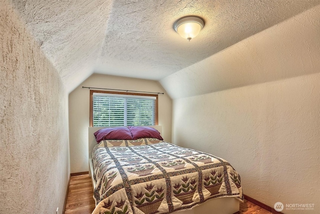 14938 Frenchie Ln SE, Yelm, WA 98597 - bedroom with wood finished floors, vaulted ceiling, a textured wall, and a textured ceiling