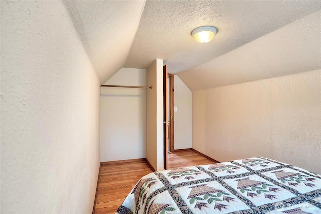 14938 Frenchie Ln SE, Yelm, WA 98597 - bedroom featuring light wood-style floors, lofted ceiling, a textured wall, and a textured ceiling