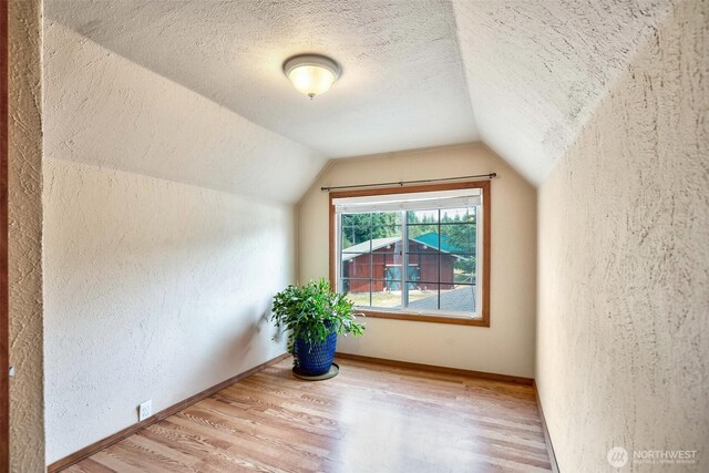 14938 Frenchie Ln SE, Yelm, WA 98597 - bonus room with a textured wall, light wood-type flooring, vaulted ceiling, and a textured ceiling