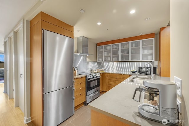 98 Union St Unit 301, Seattle, WA 98101 - kitchen featuring stainless steel appliances, wall chimney exhaust hood, a sink, glass insert cabinets, and light countertops