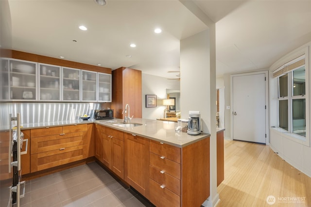 98 Union St Unit 301, Seattle, WA 98101 - kitchen with a sink, glass insert cabinets, black microwave, light countertops, and a peninsula