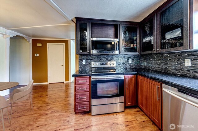 5611 128th Pl SE, Everett, WA 98208 - kitchen with appliances with stainless steel finishes, backsplash, glass insert cabinets, light wood-style flooring, and dark countertops