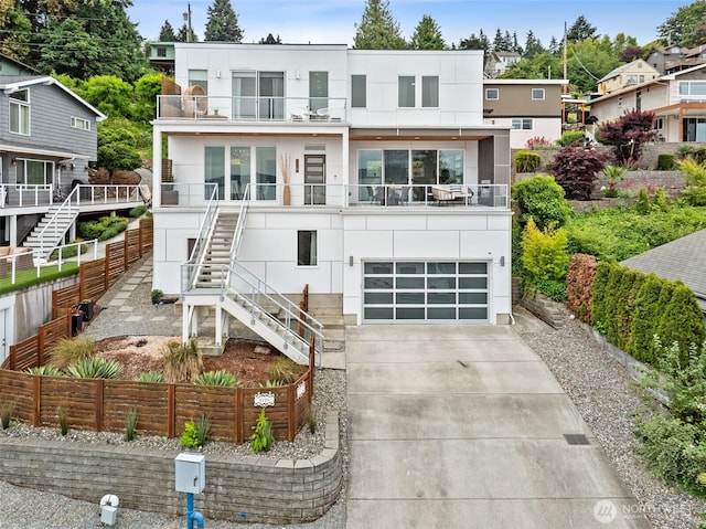 6720 Soundview Dr NE, Tacoma, WA 98422 - modern home with a balcony, stairway, concrete driveway, an attached garage, and stucco siding