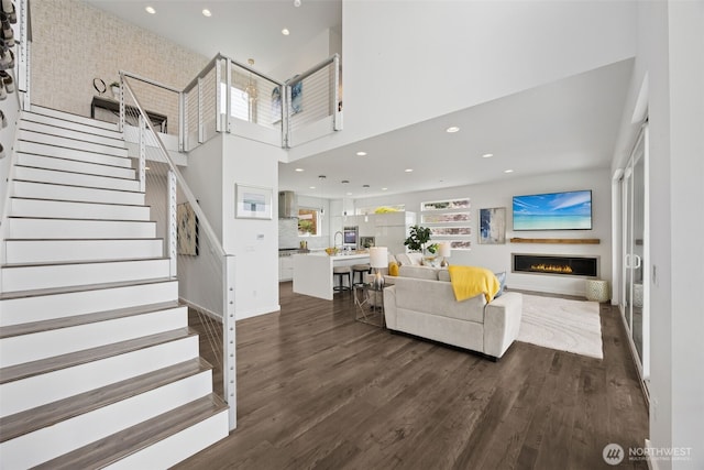 6720 Soundview Dr NE, Tacoma, WA 98422 - living area with dark wood-style flooring, a warm lit fireplace, stairway, recessed lighting, and a towering ceiling
