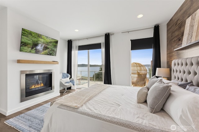 6720 Soundview Dr NE, Tacoma, WA 98422 - bedroom featuring access to exterior, a glass covered fireplace, wood finished floors, recessed lighting, and a water view