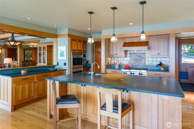 481 Grimes Riker Ln, Lopez Island, WA 98261 - kitchen with dark countertops, custom range hood, a large island with sink, decorative backsplash, and recessed lighting