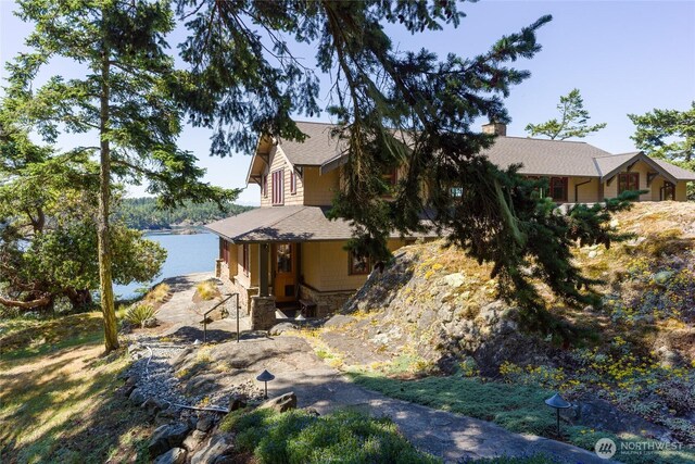 481 Grimes Riker Ln, Lopez Island, WA 98261 - view of front of house featuring a chimney, stone siding, and a shingled roof