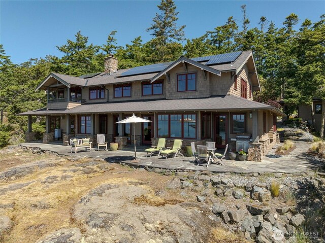 481 Grimes Riker Ln, Lopez Island, WA 98261 - view of front facade featuring a patio, a chimney, a balcony, and roof mounted solar panels