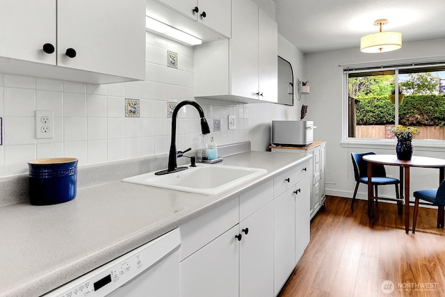 21120 77th Pl W Unit 104, Edmonds, WA 98026 - kitchen featuring a sink, dishwasher, light countertops, white cabinetry, and tasteful backsplash