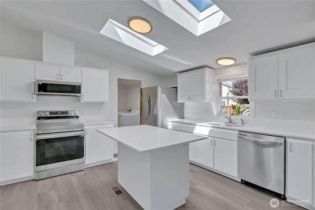 7725 203rd Street Ct E Unit 27, Spanaway, WA 98387 - kitchen with appliances with stainless steel finishes, a skylight, washing machine and dryer, light wood finished floors, and lofted ceiling