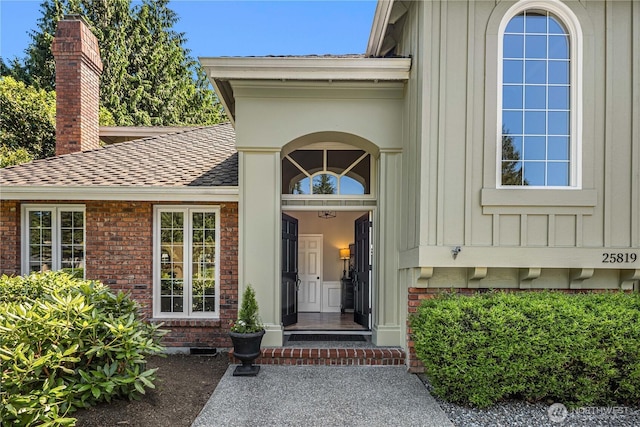 25819 NE 9th St, Sammamish, WA 98074 - view of exterior entry with board and batten siding, brick siding, roof with shingles, and a chimney