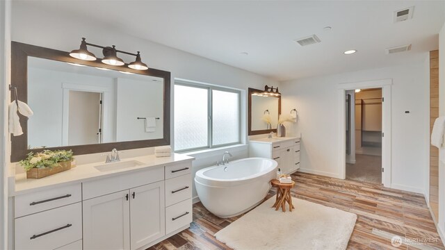 25625 SE Olympic Ln, Black Diamond, WA 98010 - bathroom with two vanities, wood finished floors, a freestanding tub, recessed lighting, and baseboards