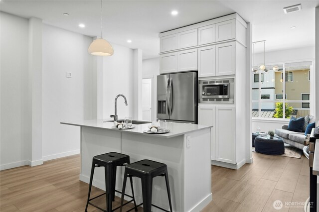 189 Countryman Dr, Monroe, WA 98272 - kitchen featuring appliances with stainless steel finishes, a sink, light wood finished floors, white cabinetry, and a breakfast bar