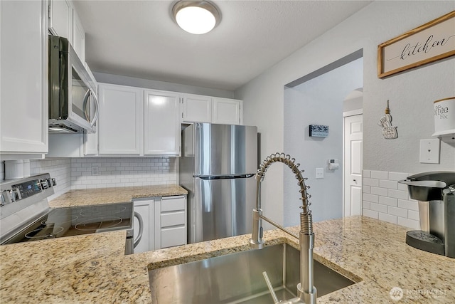 17311 119th Ln SE Unit J4, Renton, WA 98058 - kitchen featuring appliances with stainless steel finishes, a sink, tasteful backsplash, white cabinets, and light stone countertops