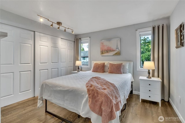 17311 119th Ln SE Unit J4, Renton, WA 98058 - bedroom featuring a closet, wood finished floors, baseboards, and rail lighting