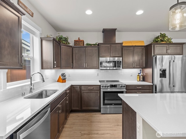 752 Parkland Loop, Sedro Woolley, WA 98284 - kitchen featuring appliances with stainless steel finishes, dark brown cabinetry, light wood-style flooring, decorative backsplash, and recessed lighting