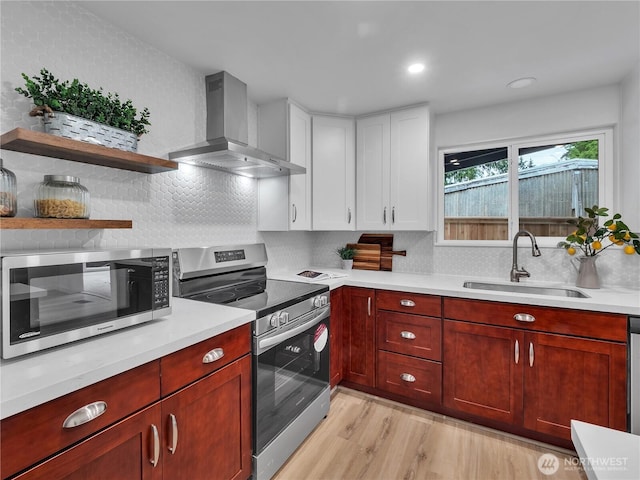 16112 Densmore Ave N, Shoreline, WA 98133 - kitchen featuring stainless steel appliances, wall chimney range hood, a sink, light wood-style flooring, and light countertops