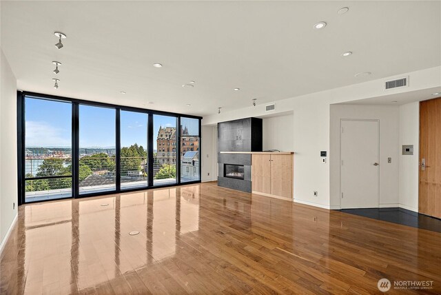 302 N Stadium Way Unit 302, Tacoma, WA 98403 - unfurnished living room featuring wood finished floors, healthy amount of natural light, recessed lighting, floor to ceiling windows, and a fireplace