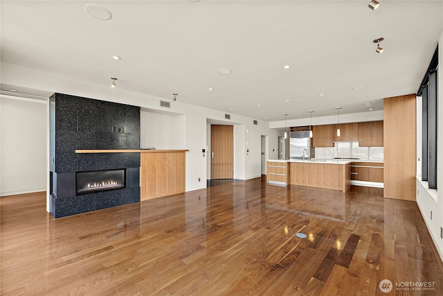 302 N Stadium Way Unit 302, Tacoma, WA 98403 - unfurnished living room with wood finished floors, a tiled fireplace, a sink, baseboards, and recessed lighting