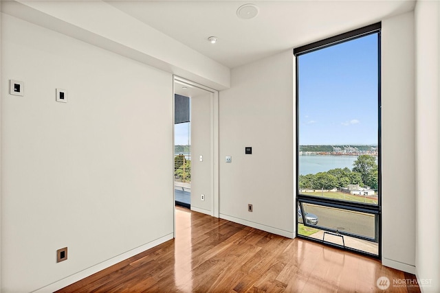 302 N Stadium Way Unit 302, Tacoma, WA 98403 - unfurnished room with wood finished floors, a wall of windows, a water view, and baseboards