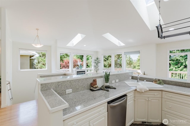 2921 Haggin St, Bellingham, WA 98226 - kitchen with a skylight, stainless steel dishwasher, a sink, white cabinetry, and pendant lighting