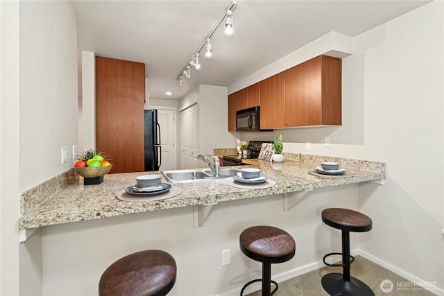 11309 NE 128th St Unit F302, Kirkland, WA 98034 - kitchen with black appliances, a sink, brown cabinets, a peninsula, and baseboards