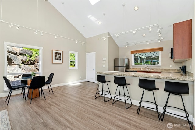 11309 NE 128th St Unit F302, Kirkland, WA 98034 - kitchen featuring freestanding refrigerator, high vaulted ceiling, a peninsula, a kitchen bar, and light wood-style floors
