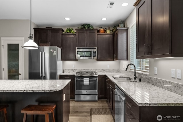 22412 SE 283rd St, Maple Valley, WA 98038 - kitchen featuring appliances with stainless steel finishes, dark brown cabinets, light wood finished floors, a breakfast bar, and decorative light fixtures