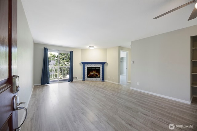 1132 N 198th St Unit C204, Shoreline, WA 98133 - unfurnished living room featuring wood finished floors, a warm lit fireplace, and a ceiling fan