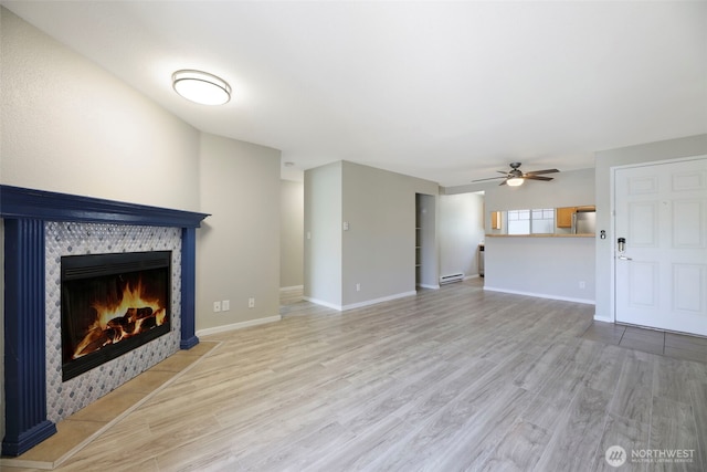 1132 N 198th St Unit C204, Shoreline, WA 98133 - unfurnished living room featuring a fireplace with flush hearth, ceiling fan, a baseboard heating unit, and light wood-type flooring