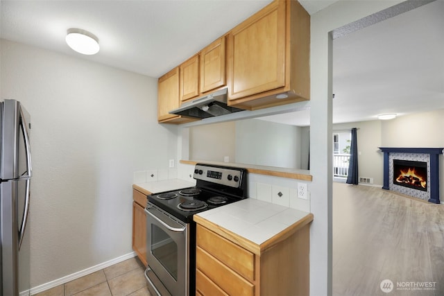 1132 N 198th St Unit C204, Shoreline, WA 98133 - kitchen with stainless steel appliances, under cabinet range hood, tile countertops, a fireplace with flush hearth, and open floor plan