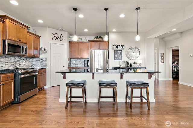 2237 55th St SE, Auburn, WA 98092 - kitchen with appliances with stainless steel finishes, dark countertops, brown cabinetry, a breakfast bar area, and decorative backsplash